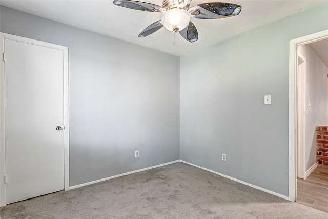 empty room with light carpet, ceiling fan, and a textured ceiling