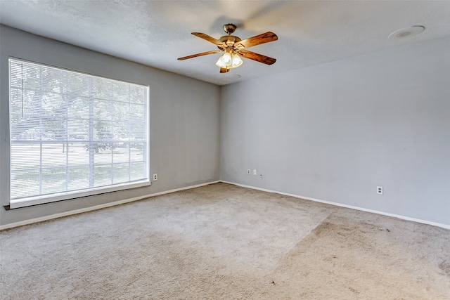 carpeted empty room featuring a textured ceiling, a wealth of natural light, and ceiling fan