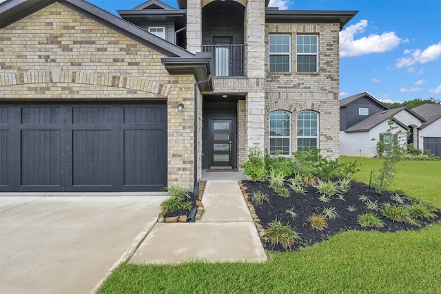 view of front of home featuring a front yard, a balcony, and a garage