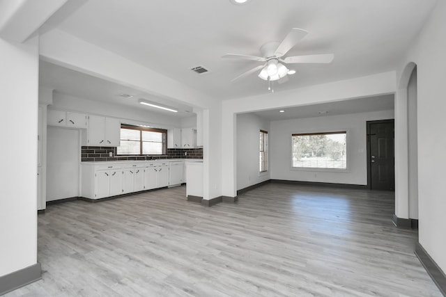 unfurnished living room featuring ceiling fan, light hardwood / wood-style floors, and a wealth of natural light