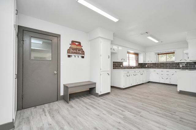 kitchen featuring white cabinets, backsplash, and light hardwood / wood-style flooring