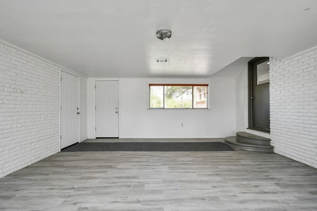 interior space featuring light hardwood / wood-style flooring and brick wall