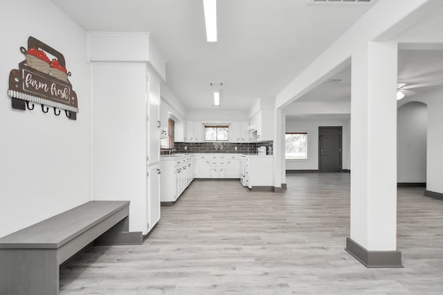 kitchen featuring decorative backsplash, light hardwood / wood-style flooring, white cabinetry, and ceiling fan