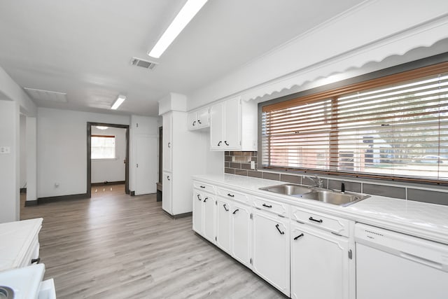 kitchen with white dishwasher, white cabinets, and a wealth of natural light