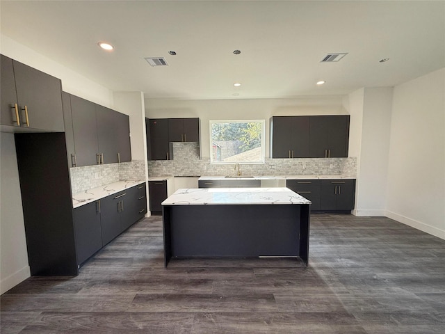 kitchen with a kitchen island, decorative backsplash, dark wood-type flooring, and sink