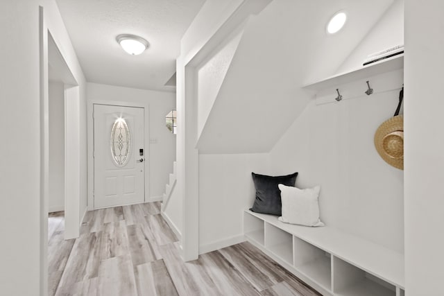 mudroom with a textured ceiling, lofted ceiling, and light hardwood / wood-style flooring