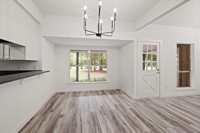 unfurnished dining area featuring light wood-type flooring, beam ceiling, and a healthy amount of sunlight