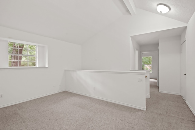 carpeted empty room with vaulted ceiling with beams and a healthy amount of sunlight