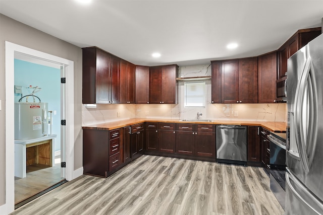 kitchen with wooden counters, light wood-type flooring, sink, stainless steel appliances, and backsplash