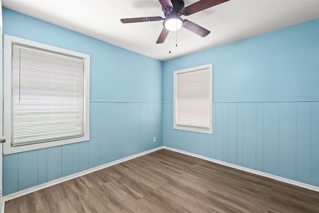 spare room featuring dark hardwood / wood-style floors, wooden walls, and ceiling fan