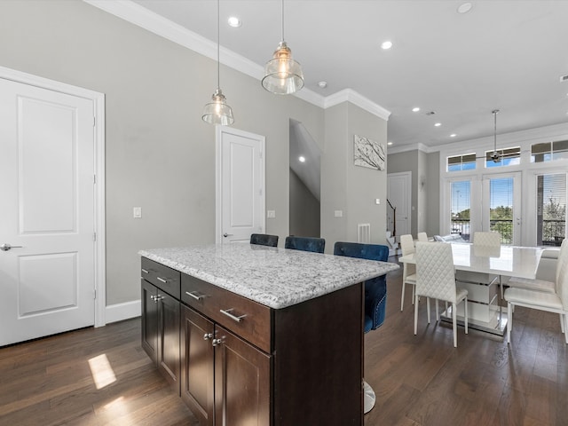 kitchen with dark brown cabinetry, pendant lighting, a kitchen island, dark wood-type flooring, and a kitchen breakfast bar