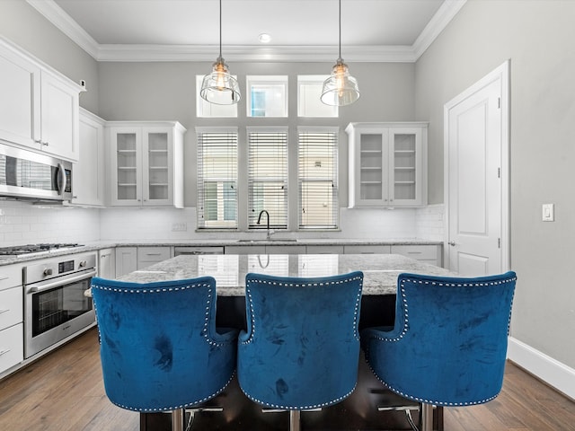 kitchen with white cabinets, a center island, appliances with stainless steel finishes, dark hardwood / wood-style floors, and a breakfast bar