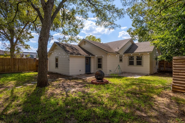 back of property with a yard, a patio area, and an outdoor fire pit