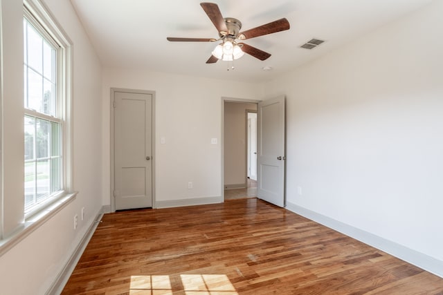 unfurnished room with ceiling fan, hardwood / wood-style flooring, and a wealth of natural light