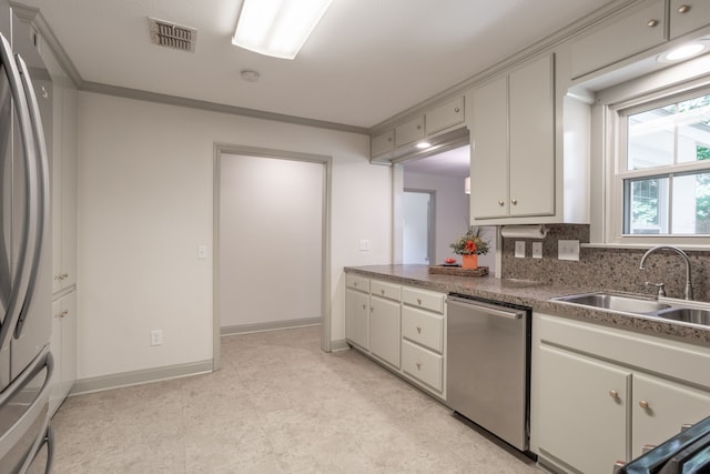 kitchen featuring appliances with stainless steel finishes, backsplash, sink, and crown molding