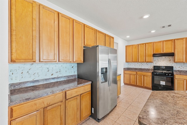 kitchen with stainless steel fridge, gas stove, backsplash, light tile patterned floors, and a textured ceiling