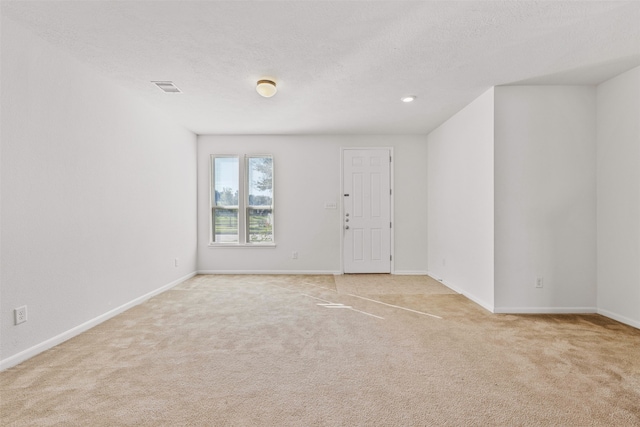 carpeted empty room with a textured ceiling