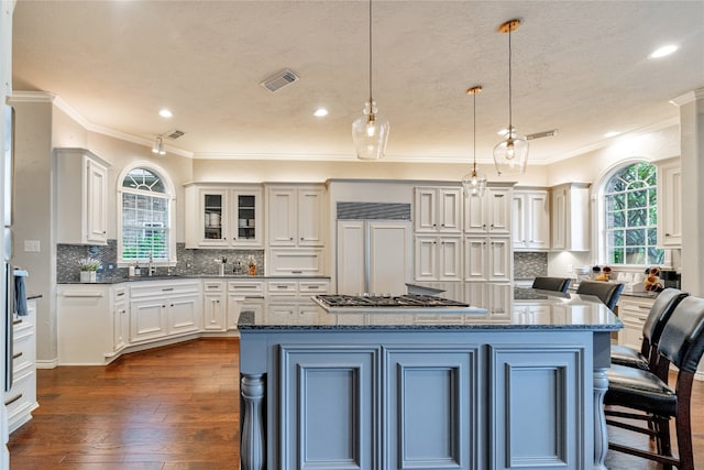 kitchen with crown molding, decorative light fixtures, dark hardwood / wood-style flooring, and a center island