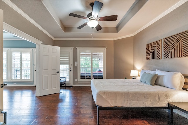 bedroom featuring ceiling fan, a raised ceiling, dark wood-type flooring, and multiple windows