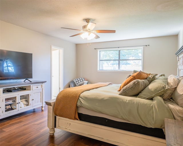 bedroom with ceiling fan, dark hardwood / wood-style floors, and a textured ceiling