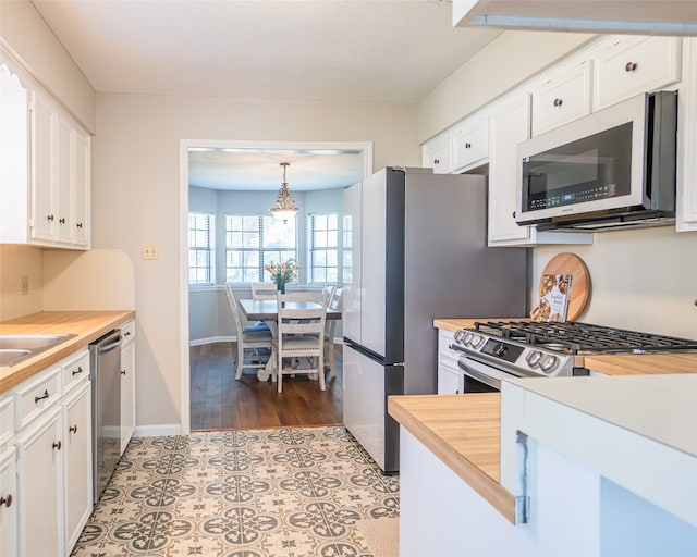 kitchen featuring butcher block counters, hanging light fixtures, dark hardwood / wood-style flooring, white cabinets, and appliances with stainless steel finishes