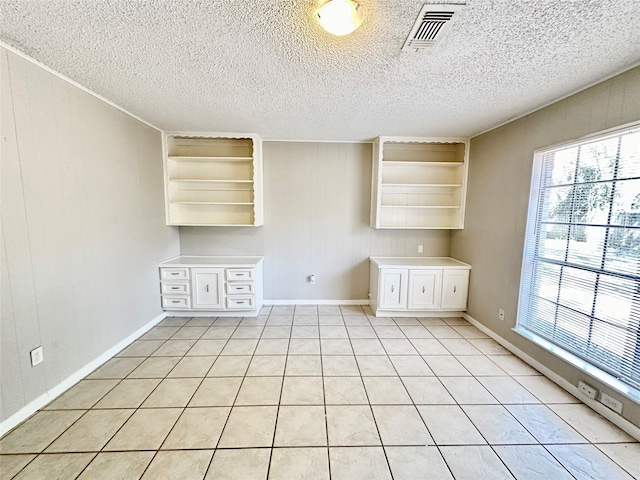 empty room featuring a textured ceiling, wooden walls, and light tile patterned floors