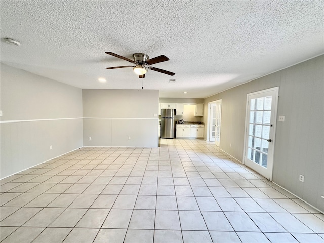 unfurnished living room featuring ceiling fan, a textured ceiling, and light tile patterned floors