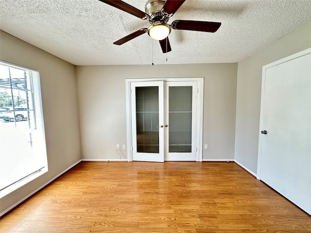 unfurnished room with a textured ceiling, ceiling fan, french doors, and light hardwood / wood-style flooring