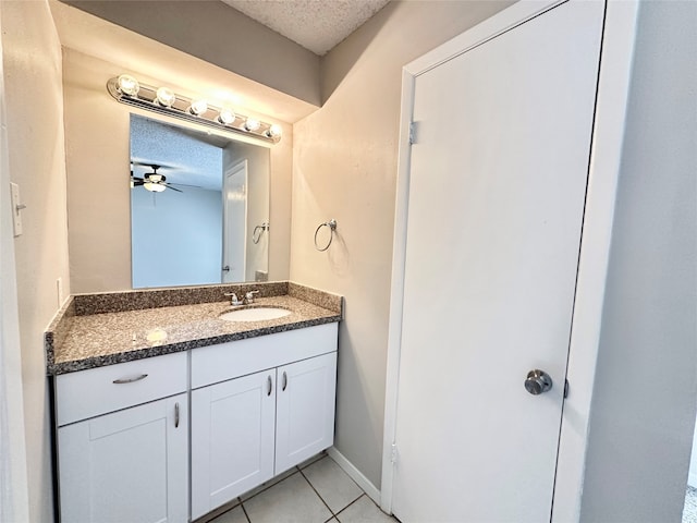 bathroom with tile patterned flooring, ceiling fan, vanity, and a textured ceiling