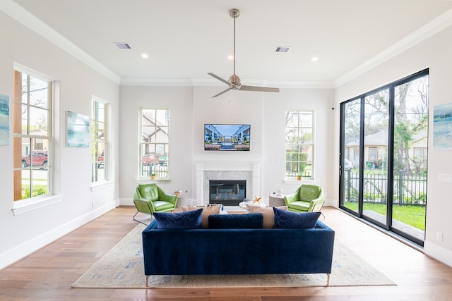 living room with light wood-type flooring, a healthy amount of sunlight, and crown molding