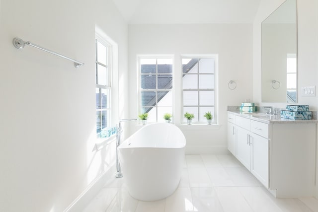 bathroom featuring vanity, tile patterned floors, a bath, and a healthy amount of sunlight