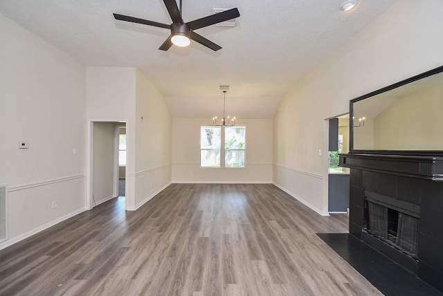 unfurnished living room with hardwood / wood-style flooring, ceiling fan with notable chandelier, and lofted ceiling