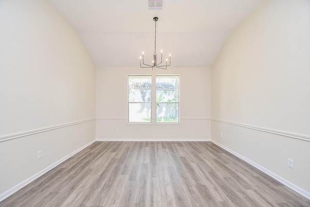 empty room with a chandelier, light wood-type flooring, and lofted ceiling