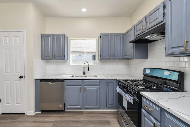 kitchen featuring backsplash, light stone counters, stainless steel appliances, dark wood-type flooring, and sink