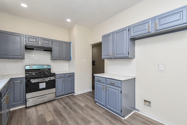 kitchen featuring light stone countertops, gas range, dark hardwood / wood-style flooring, and decorative backsplash