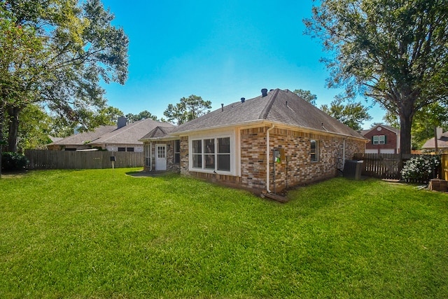 rear view of property featuring a lawn and central AC unit