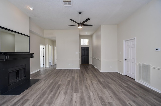 unfurnished living room featuring hardwood / wood-style floors, ceiling fan, and a high ceiling