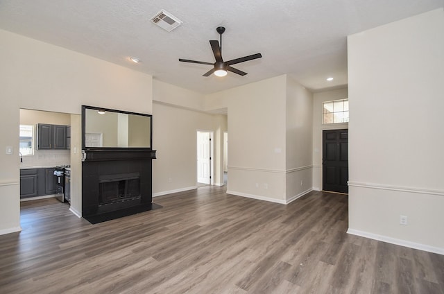 unfurnished living room featuring ceiling fan and dark wood-type flooring