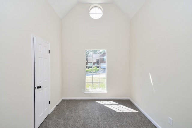 carpeted spare room featuring high vaulted ceiling