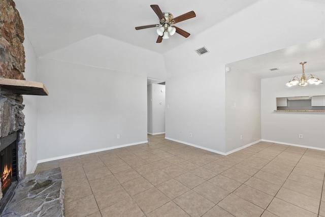 unfurnished living room with a stone fireplace, light tile patterned flooring, ceiling fan with notable chandelier, and vaulted ceiling