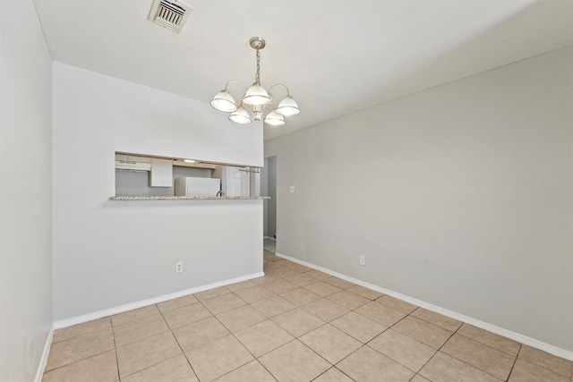 empty room featuring a notable chandelier and light tile patterned floors