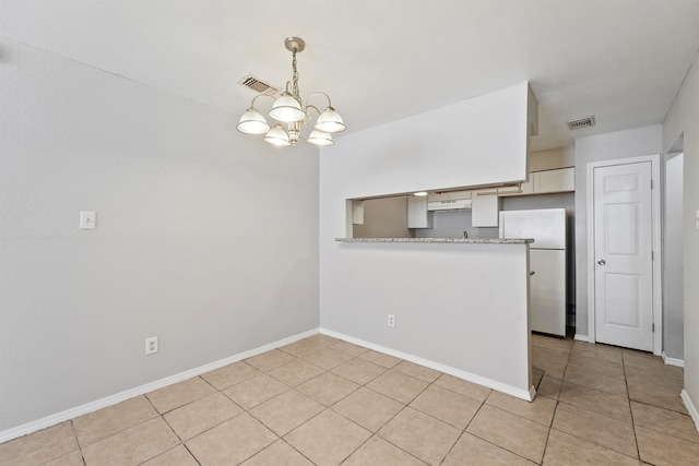 kitchen featuring exhaust hood, light tile patterned flooring, kitchen peninsula, white fridge, and a chandelier