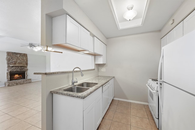 kitchen featuring light tile patterned floors, sink, white appliances, white cabinetry, and a fireplace