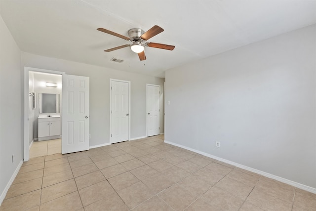 unfurnished bedroom with ceiling fan, ensuite bath, and light tile patterned floors