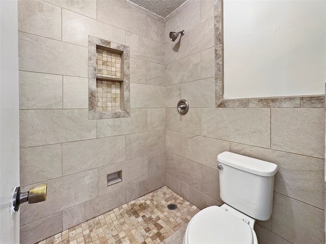 bathroom featuring tile walls, a tile shower, and toilet