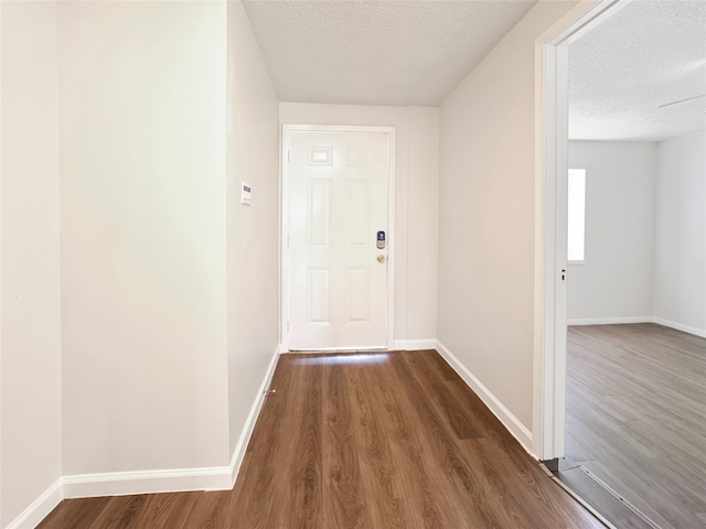 hallway with dark hardwood / wood-style floors and a textured ceiling