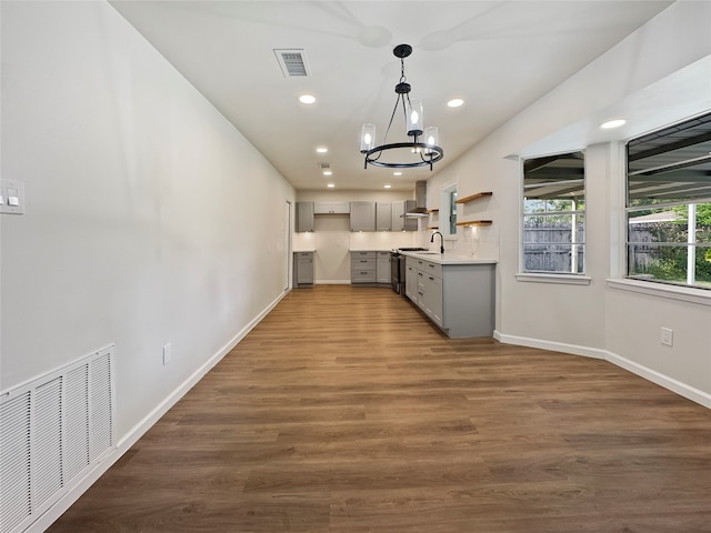 kitchen with an inviting chandelier, gray cabinets, dark hardwood / wood-style flooring, and wall chimney range hood