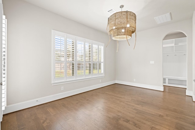 unfurnished dining area with wood-type flooring and an inviting chandelier