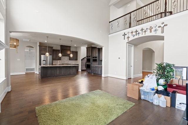 living room with dark wood-type flooring and a high ceiling