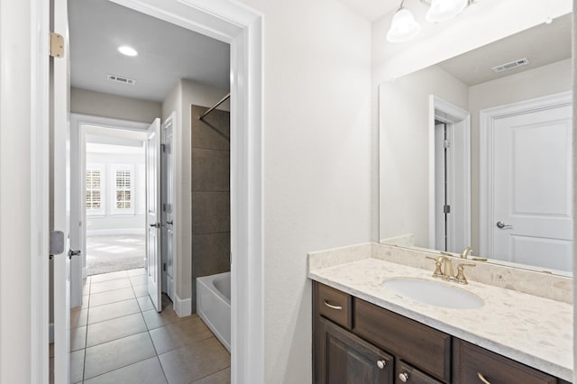 bathroom with tile patterned floors, vanity, and tiled shower / bath combo